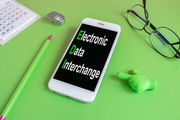 EDI electronic data interchange symbol. Concept words Electronic Data Interchange written on the mobile phone screen. Beautiful green background. Glasses, coins. Business concept.