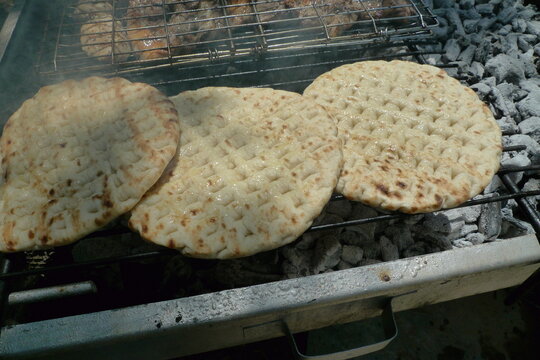 Three greek pita breads grilled over hot coals, horizontal photo, top view