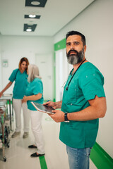 Fototapeta premium Male doctor with tablet in hospital hallway with colleagues.