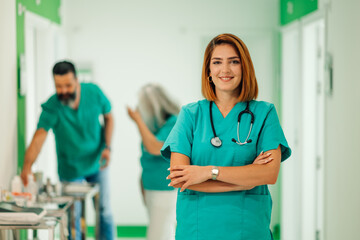 Confident female doctor standing in a hospital hallway, colleagues behind