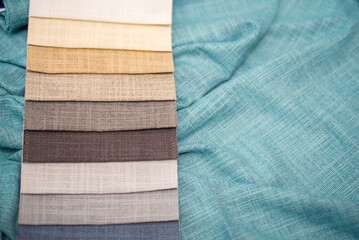 Beige and gray samples of fabrics for curtains on a turquoise background. Linen fabric.