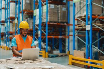 Attentive african american male worker using laptop for logistical operations.