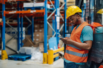 African american male warehouse worker using smartphone during break time.