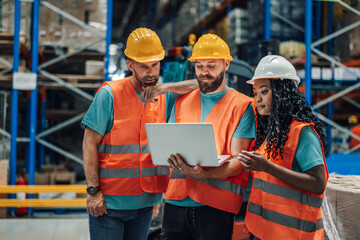 Team of workers analyzing data on a laptop in warehouse