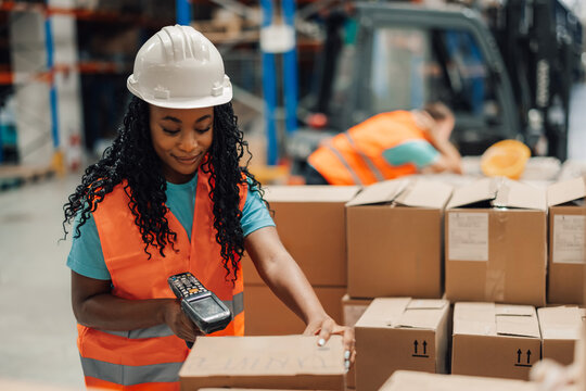 African american female warehouse worker scanning boxes with handheld scanner.