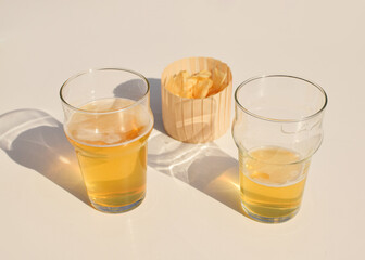 Two glasses of beer and chips in a paper cup.