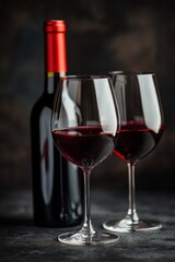Elegant red wine glass in front of blurred wine bottles on dark background at evening