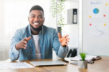 Smiling african american business coach sharing his experience and creative ideas at camera,...