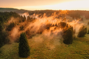 Aerial sunrise on the plain with fog and trees on the meadow. Summer landscape from Poiana Brasov, ski resort, Romania
