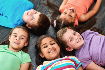 Above, circle and portrait of children on floor for playing, friendship and bonding in classroom. Diversity, youth and group of kids with smile for learning, education and development at school