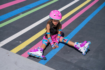 A girl upset by a roller skating failure. A child in a helmet and full sports gear