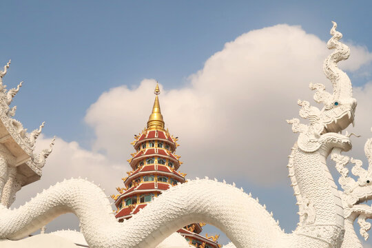 View onto the Phop Chok Dhamma Chedi, part of the Wat Huay Pla Kang Temple Complex, rising behind two white thai dragons, phaya nagas, Chiang Rai, Thailand