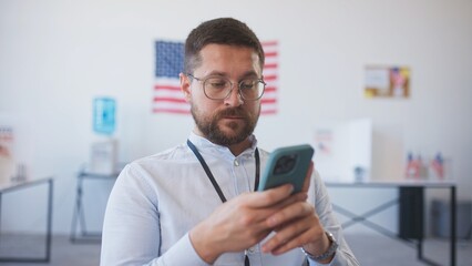 Close frontal camera view of Caucasian man with beard and glasses texting on mobile phone with...