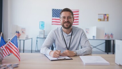 Camera moving closer to Caucasian male with beard and glasses sitting at desk. Finishing filling...