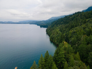 Aerial View of Cultus Lake, BC, Canada Coastline Showing Turquoise Water with a Boat and Mountains on a Cloudy Day. Summer turning to Autumn.