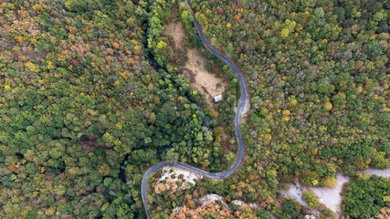 Petite route sauvage de montagne longeant une petite rivière. La route serpente le long de cette...
