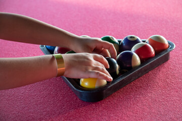 A boy's hand arranging pool balls