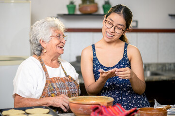 Grandma is happy to show her granddaughter how to make corn tortillas.