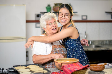 The Latina grandmother enjoys the loving hug her granddaughter gives her.