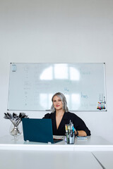 Portrait of a young beautiful English teacher working at school, at her desk in the classroom.
