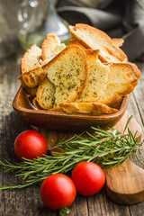 Crispy roasted bruschetta bread in bowl on wooden table.