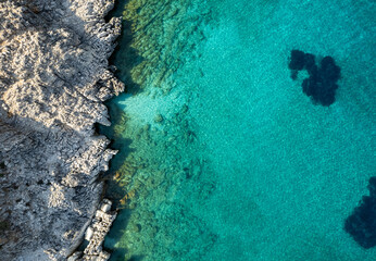 Turquoise water meeting rocky coastline on sunny summer day