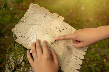 The pirate map.Children's outdoor quest. Search for pirate treasures.Point your finger at the buried treasure.