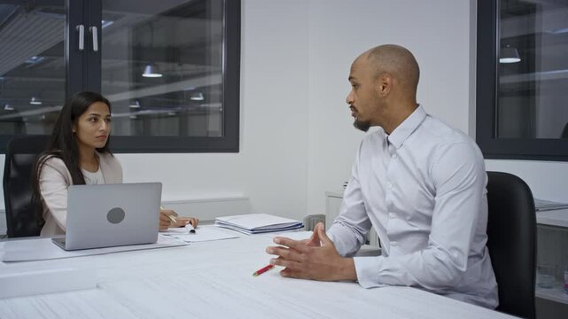 Indian female hiring manager shaking hands with an African American male candidate at the end of a successful job interview, handheld shot.