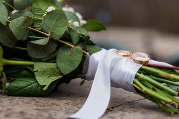 Elegant Wedding Bouquet adorned with Gold Wedding Rings and Fresh Greenery