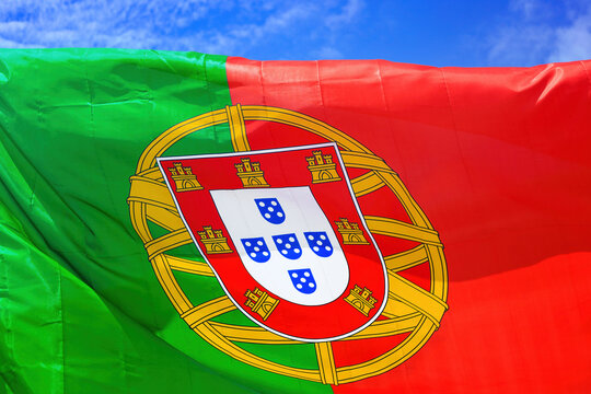 Bandeira portuguesa a ondular ao vento num c&eacute;u azul. 