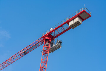 Red construction crane against a clear blue sky at a building site