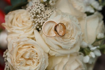 Elegant wedding rings resting on a bouquet of soft cream roses adorned with delicate baby's breath