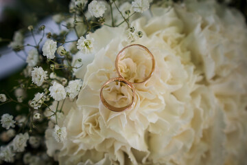 Elegant Wedding Rings Resting on Creamy Floral Arrangement with Delicate White Accents