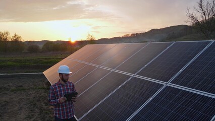 Solar panels field maintenance work with smart tablet app device. Engineer checking the site after installation. Eco sustainable alternative green energy