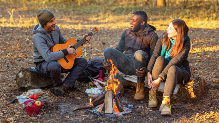 International group of people camping and singing in autumn forest, copy space