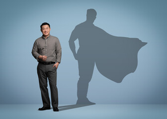 Confident businessman casting shadow of superhero on light blue background. Success, power, leadership and determination concepts © New Africa