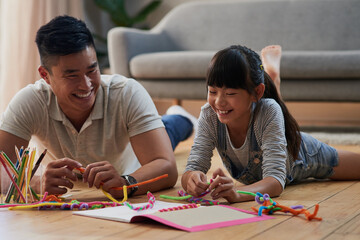 Asian father, girl and homework on floor with art, color and happy for school project in living room. People, dad and daughter child with books, laugh and development for scholarship in family home