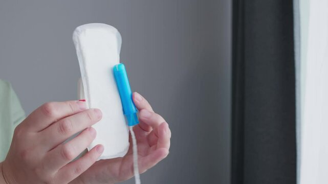 woman hands holding pad and tampon making decision of hygienic products. Different types of feminine menstrual hygiene materials 