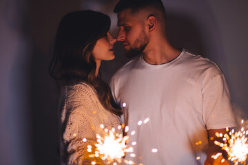 Beautiful loving couple celebrating Christmas or New Year eve at home. Happy young boyfriend and girlfriend spending time together, making wishes, kissing. Concept of love, celebration, happiness