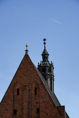 A historic church steeple rises against a clear blue sky, with a jet trail visible above. This image captures architectural elegance and the juxtaposition of tradition and modernity
