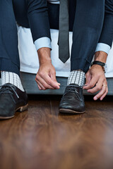 Fototapeta premium Business, hands and tie shoes on bed in home with getting ready, dressing for work or morning routine in bedroom. Professional, man and employee with designer footwear in apartment for startup career