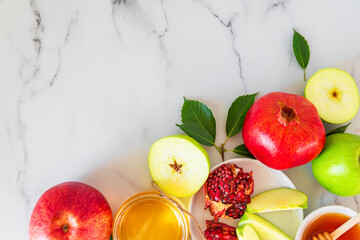 Rosh Hashana Jewish New Year holiday food with honey, pomegranate and apples on white marble background. flat lay. top view with copy space
