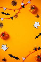 Halloween frame of bunting, ghosts, pumpkins, web, bats, spiders on orange background. Flat lay, top view,, copy space.