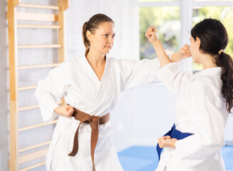 Obraz premium Adult woman and young woman karateka train karate punches in studio