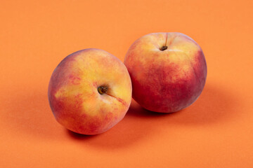 Two Fresh Peaches on Vibrant Orange Background – Minimalist Fruit Photography for Healthy Eating, Summer, and Organic Produce Concepts