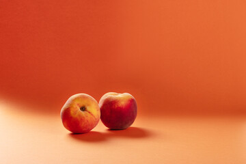 Two Fresh Peaches on Vibrant Orange Background – Minimalist Fruit Photography for Healthy Eating, Summer, and Organic Produce Concepts