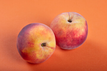 Two Fresh Peaches on Vibrant Orange Background – Minimalist Fruit Photography for Healthy Eating, Summer, and Organic Produce Concepts