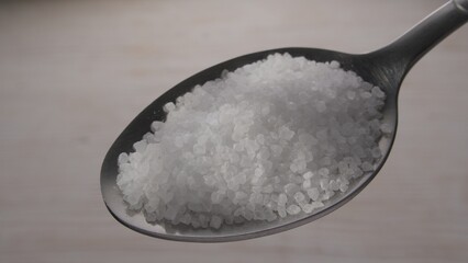 Coarse salt crystals on a silver spoon. Close-up, shallow dof.