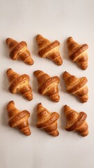 Flat lay of freshly baked golden croissants on a neutral-toned surface