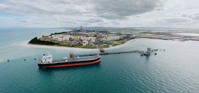 Petroleum tanker, coastline and storage silos at the decomissioned Marsden Point Refinery, Whangarei, Northland, New Zealand.